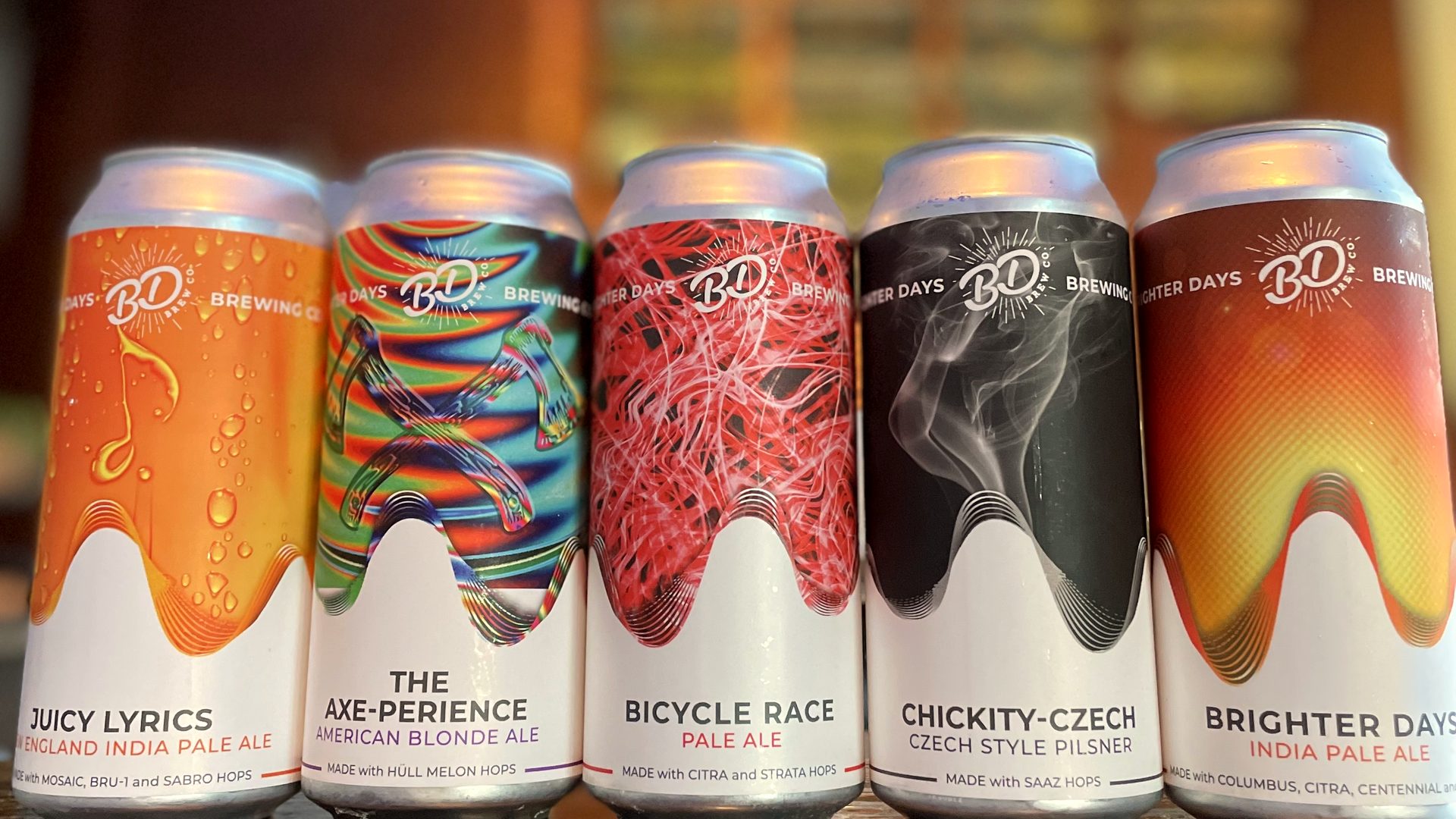 Five Brighter Days cans lined up on the bar in front of the tap wall