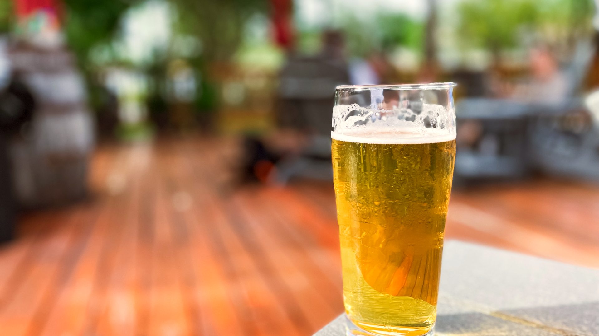 Cold pint of golden beer on a table on the deck