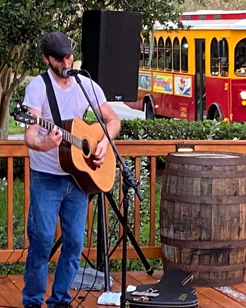 A guitarist playing on the deck as a trolley passes