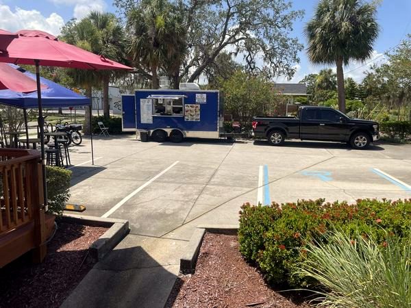 Outdoor area with red umbrellas and a food truck parked out back