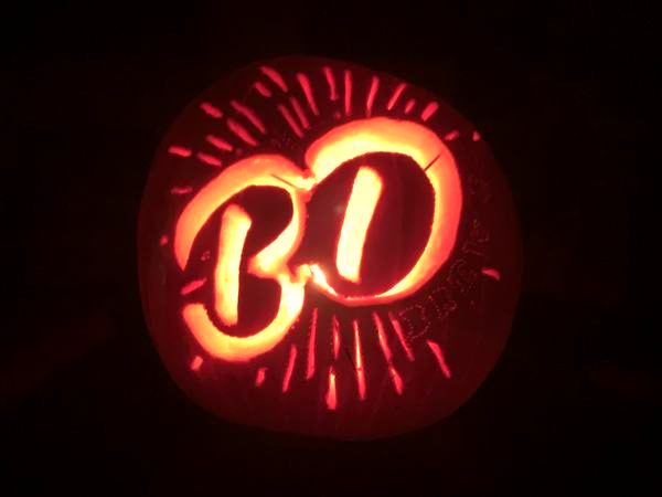 Carved pumpkin with the BD logo glowing at night