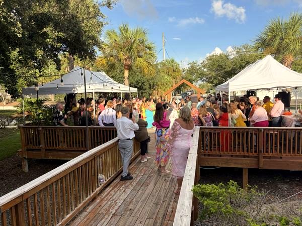 Deck with white event tents and a crowd on a sunny day