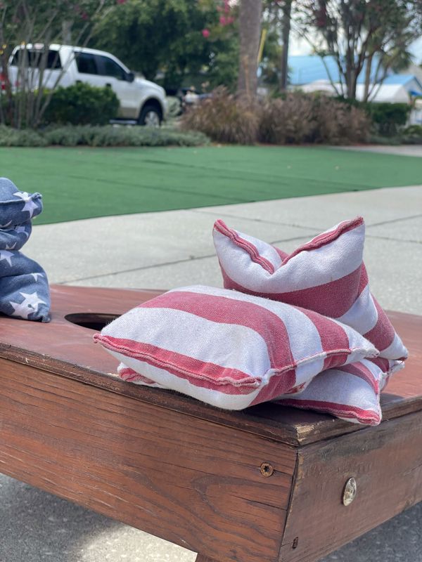 Red-and-white striped cornhole bags on a wooden board