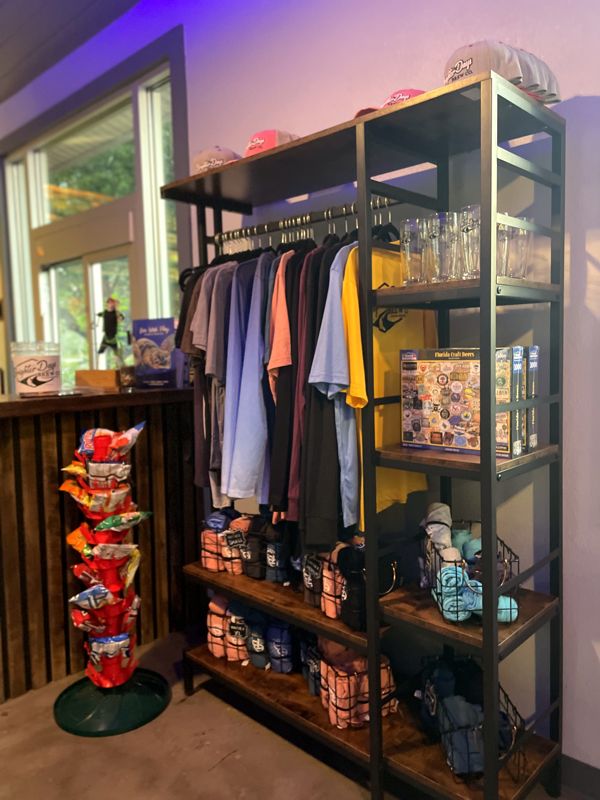 Rack of Brighter Days shirts and merchandise on shelves inside the taproom